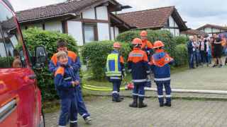 Jugendfeuerwehrleute  neben ausgelegten Schläuchen