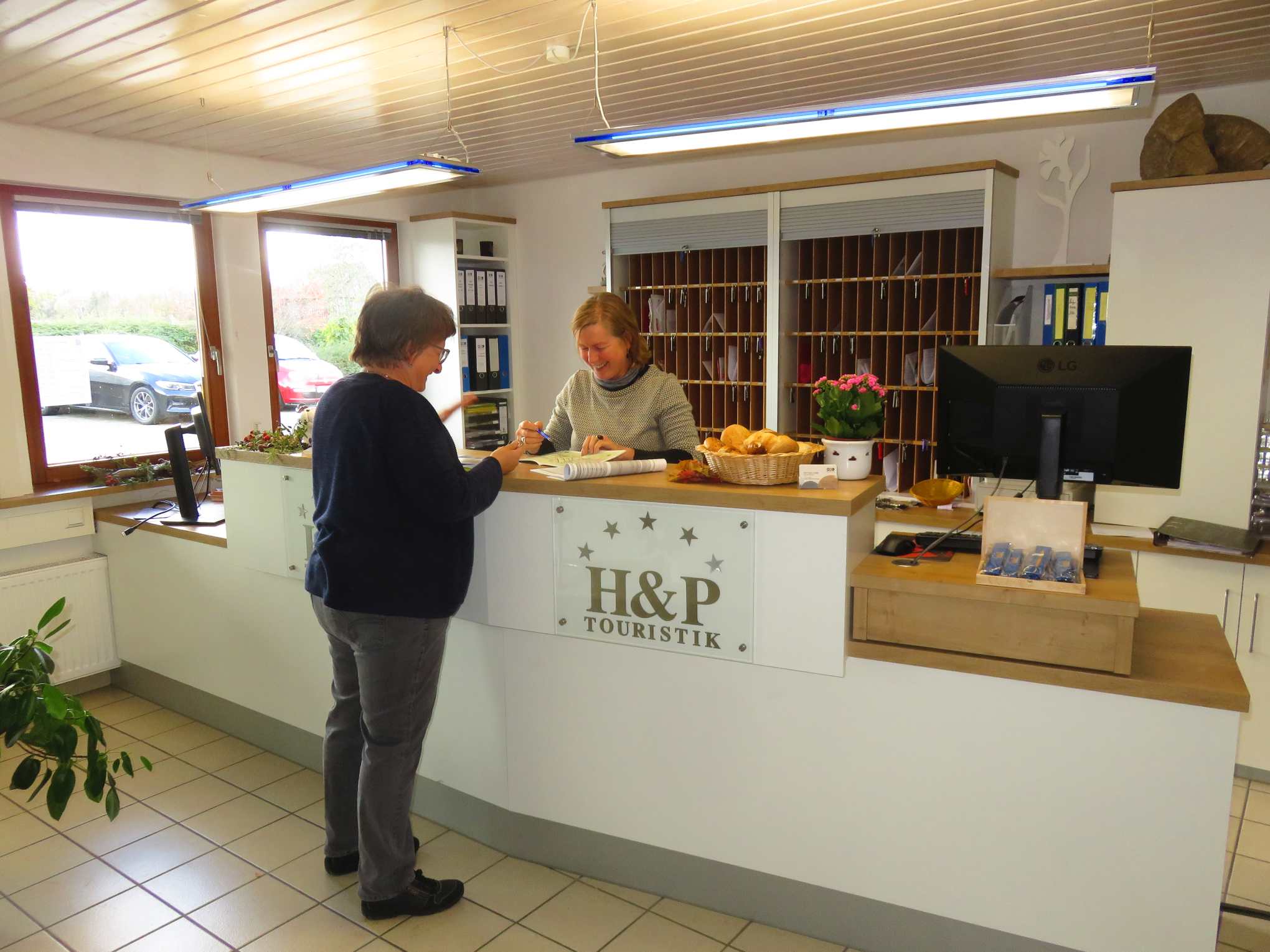 Diaschau Rezeption innen mit Gast an der Empfangstheke