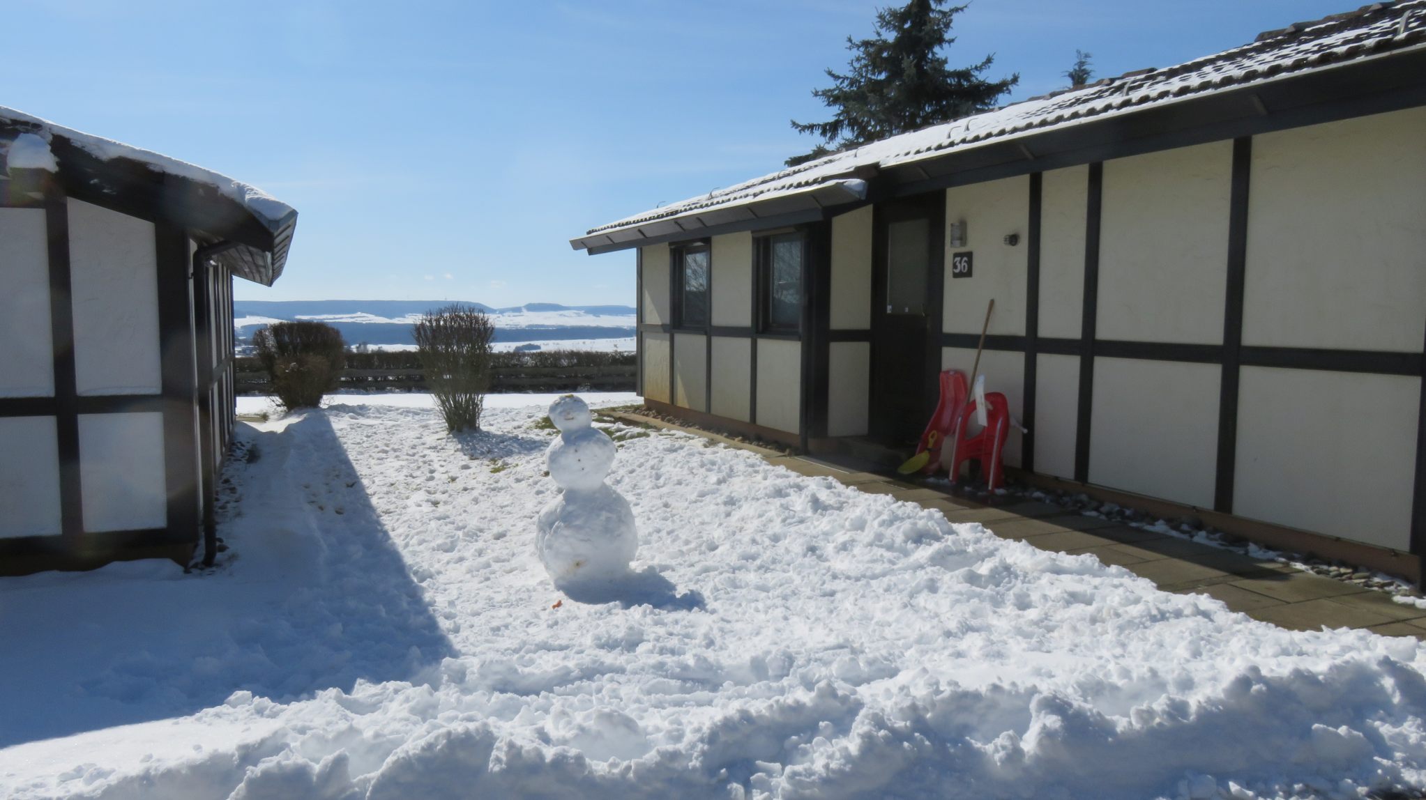 Diaschau Schnee und Schneemann zwischen zwei Ferienhäusern