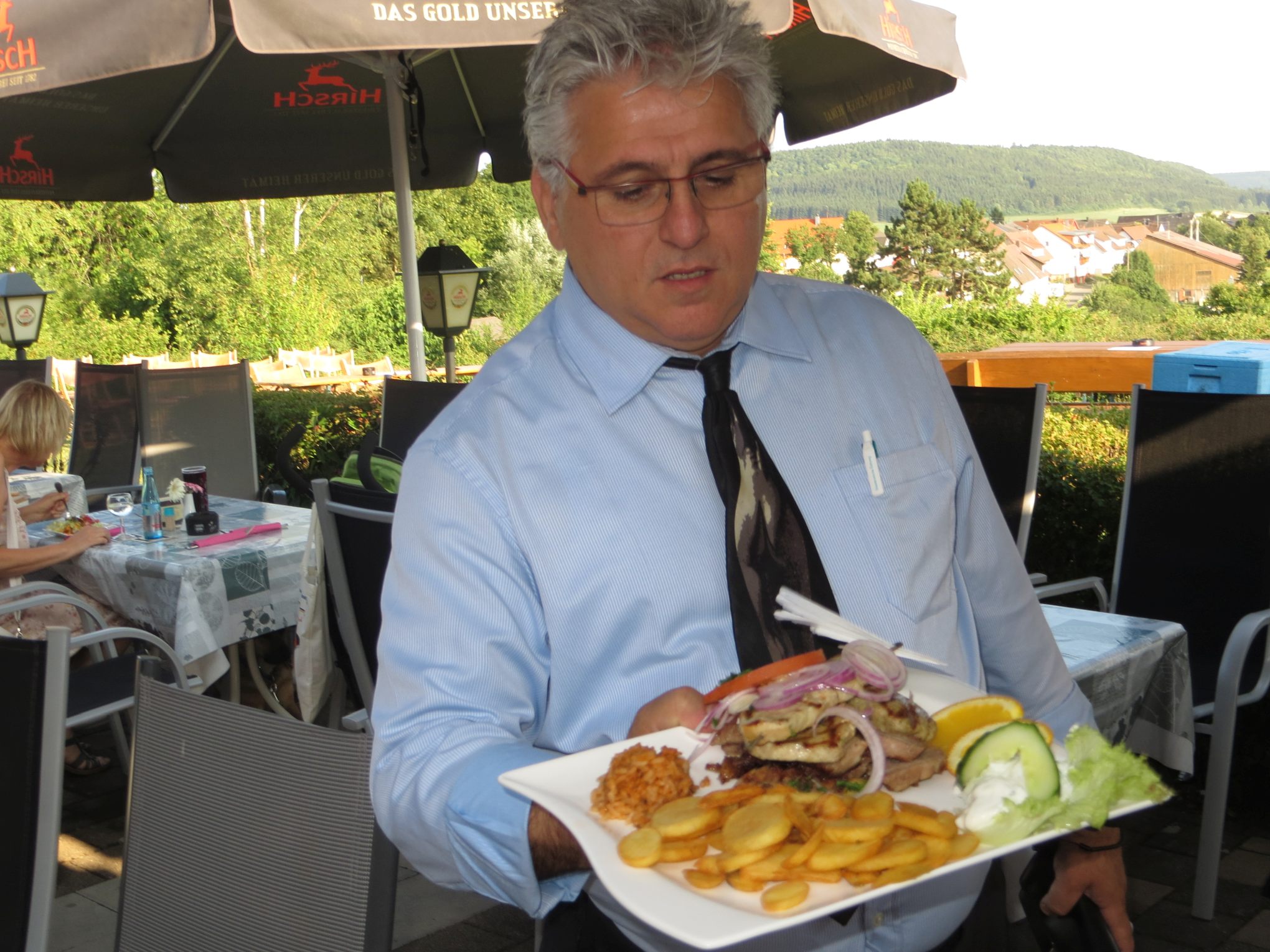 Diaschau Wirt zeigt Teller mit Essen im Landhaus